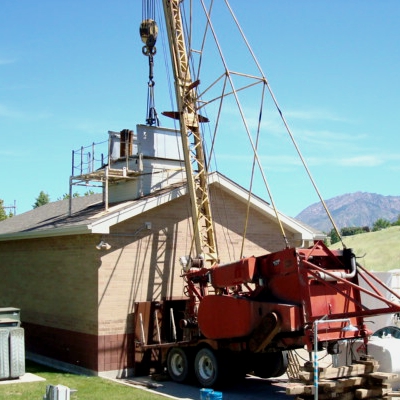 Crane installing pump in wellhouse